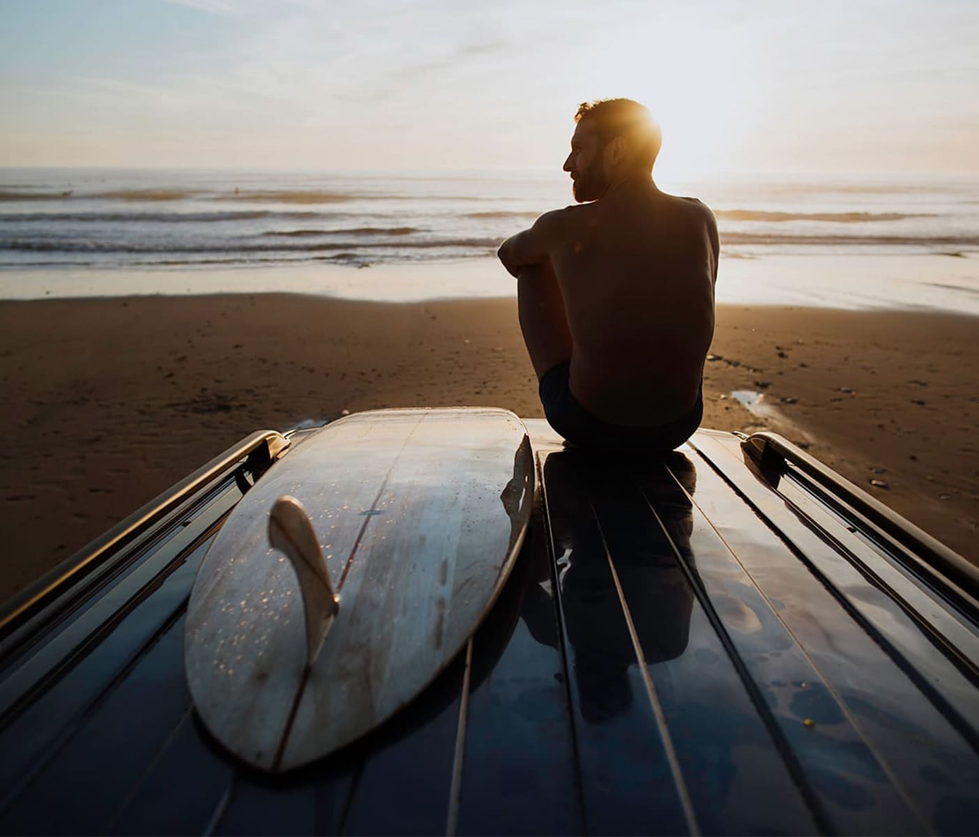 Man-sitting-on-beach-watching-ocean-wearing-Bluebuck-Nautical-trunk_